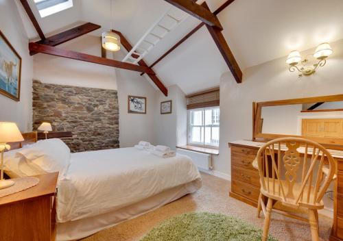 a bedroom with a bed and a desk and a chair at Wisteria Cottage in Great Torrington