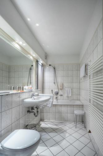 a bathroom with a toilet and a sink and a tub at Waldhotel Sonnenberg in Bollendorf