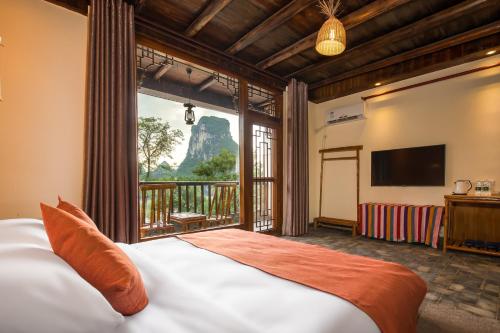 ein Schlafzimmer mit einem Bett und einem großen Fenster in der Unterkunft Yangshuo River Lodge Hotel in Yangshuo
