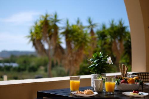 een tafel met eten en glazen sinaasappelsap bij Casa Campos Arillas in Arillas