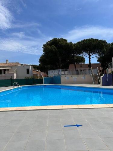 une grande piscine bleue dans une cour dans l'établissement La Pineda appt RDJ cosy à 200m du village natu, au Cap d'Agde