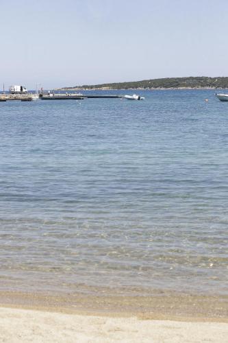 a large body of water with a beach and a boat at Bagaglino I Giardini Di Porto Cervo in Porto Cervo