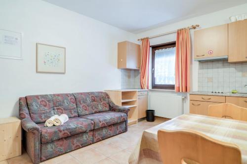 a living room with a couch and a kitchen at Apparthotel Feldhof - Living and Bistro in Nova Ponente