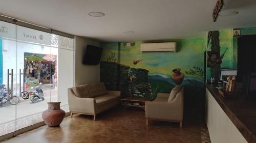 a living room with two chairs and a painting on the wall at Hotel Tayromar in Santa Marta