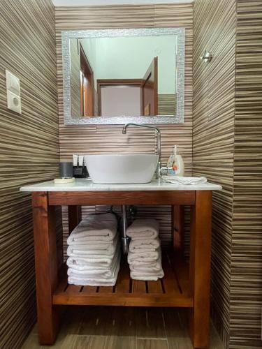 a bathroom with a sink and a mirror and towels at Aphaias Apartments in Aegina Town