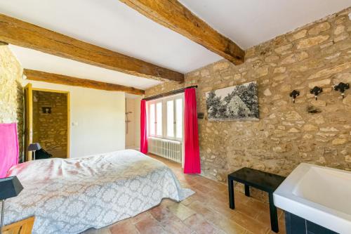 a bedroom with a bed and a stone wall at Villa spacieuse avec jardin à Saignon in Saignon