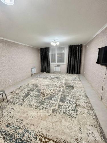 an empty living room with a large rug on the floor at Элитная новая квартира в Туркестане 2 in Türkistan