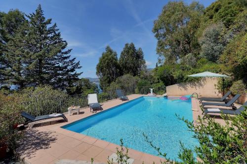 une piscine avec des chaises longues et un parasol dans l'établissement Villa des Fontenelles, à La Croix-Valmer