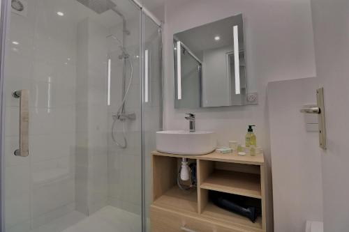a white bathroom with a sink and a shower at Villa des Fontenelles in La Croix-Valmer