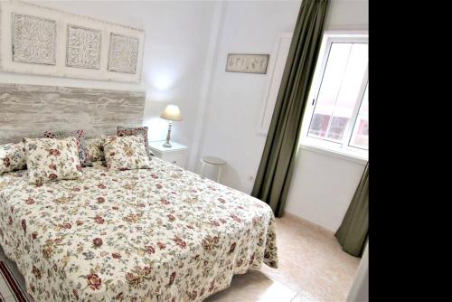 a bedroom with a bed with a floral bedspread and a window at 2 bedrooms appartement with wifi at San Cristobal de La Laguna in Las Lagunas