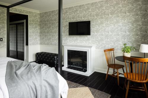 a bedroom with a fireplace and a tv on the wall at The Litchfield Inn in Litchfield