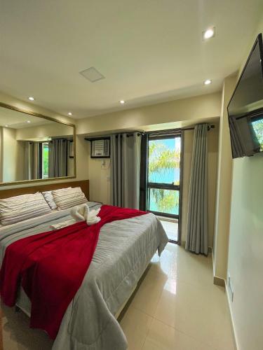 een slaapkamer met een groot bed en een rode deken bij Apartamento LUXO no Porto Real Resort ao lado da praia in Mangaratiba