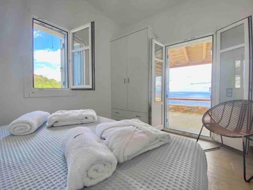Un dormitorio blanco con una cama con toallas. en Blue Calm Luxury Villa in Sifnos, en Artemonas