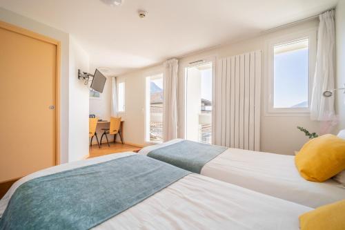 two beds in a room with two windows at Centre Jean XXIII in Annecy