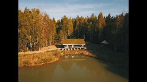 una casa sentada a un lado de un lago en Pelėdų Namelis, en Šlaveitai