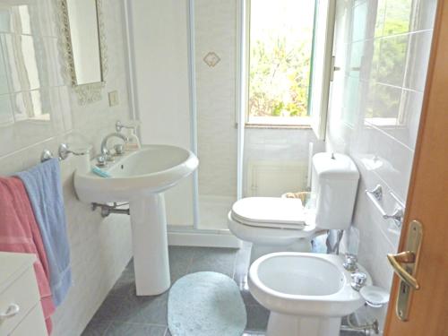 een witte badkamer met een wastafel en een toilet bij 2 bedrooms appartement with furnished terrace at Taormina 3 km away from the beach in Taormina