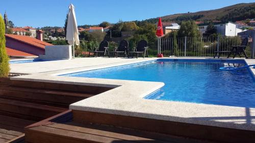 a swimming pool in a yard with chairs and umbrellas at 3 bedrooms house with private pool jacuzzi and enclosed garden at Pontevedra in Rífrío