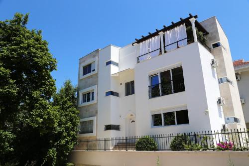 a white building with a fence and trees at One bedroom appartement at Tivat 200 m away from the beach with wifi in Tivat