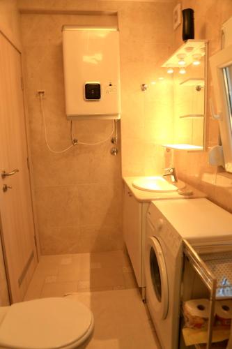 ein Badezimmer mit Toilette, Waschbecken und Waschmaschine in der Unterkunft Cozy Apartment in Tivat, 32 m² + Parking in Tivat