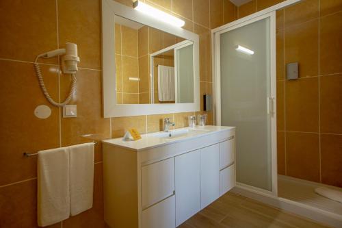 uma casa de banho com um lavatório, um espelho e um chuveiro em Hotel Rural Brícia Du Mar em Ferragudo