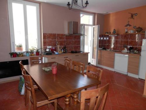 - une cuisine avec une table et des chaises en bois dans l'établissement Appartement spacieux avec grand patio, 1er étage, à Sigean