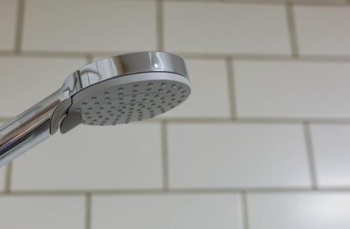 a shower head on a white tiled wall at The Cricketers Inn in Petersfield