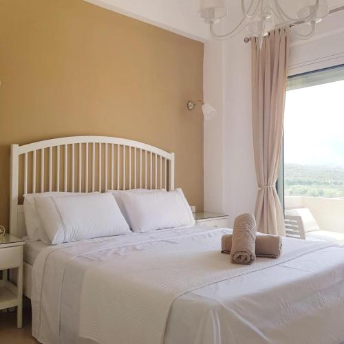 a bedroom with a large white bed with a window at Katy's Luxury Apartments in Kavros