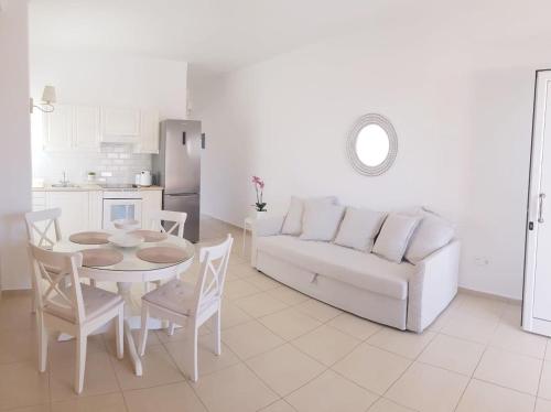 a living room with a white couch and a table and chairs at Katy's Luxury Aparments in Kavros