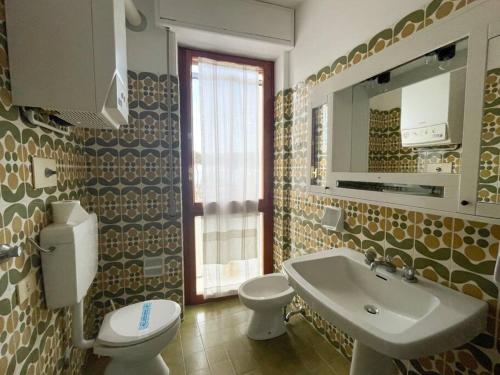 ein Badezimmer mit einem Waschbecken, einem WC und einem Spiegel in der Unterkunft Homiday - Sanpà 23 in Pineto