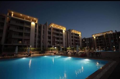 a large swimming pool in front of buildings at night at شاليه للايجار 3 غرف مكيفات بقرية جراند هيلز الساحل الشمالى بإطلاله مباشره على البول in Qaryat Shurūq