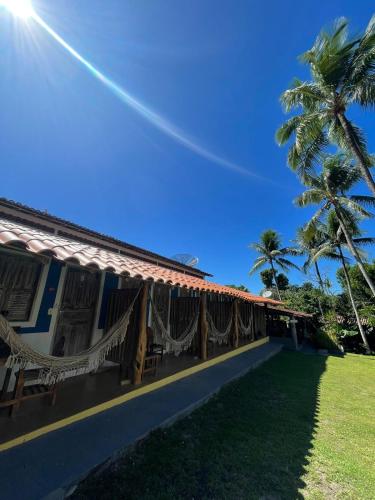 a house with hammocks and a palm tree at Céu Azul Pousada in Arraial d'Ajuda