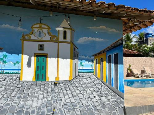 a mural of a church next to a pool at Céu Azul Pousada in Arraial d'Ajuda