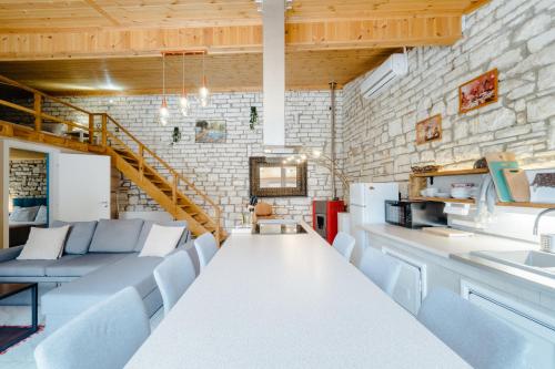 a living room with white furniture and a brick wall at Kritamos Luxury Apartment in Chrysi Ammoudia