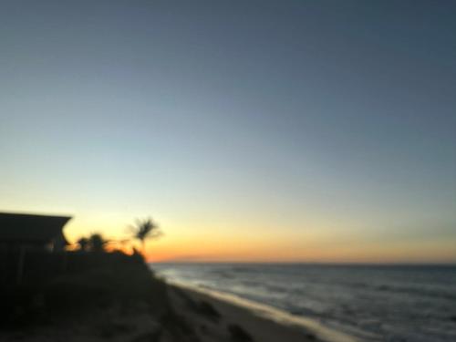 a sunset on the beach with a palm tree at Espetacular Casa de Charme em São Miguel do Gostoso - Salou in São Miguel do Gostoso