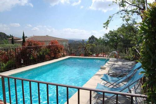 a swimming pool with two chairs and a fence at Bastide Provençale Les Mûriers d'Engaspaty in Seillans