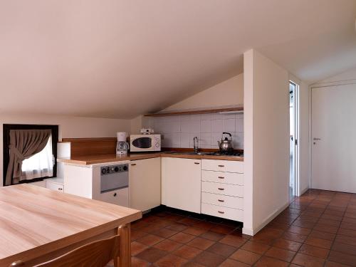 a kitchen with white cabinets and a microwave at Residence Il Melograno in Manerba del Garda