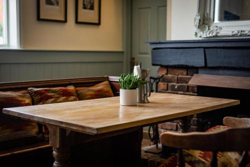 een houten tafel in een woonkamer met een piano bij The Cricketers Inn in Petersfield