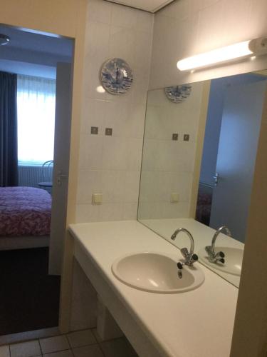 een badkamer met een wastafel, een spiegel en een bed bij Appartement Zuiderzeestate Makkum in Makkum