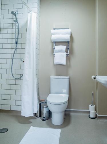 a bathroom with a toilet and a shower with towels at The Cricketers Inn in Petersfield
