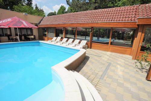 a large swimming pool with chairs and a building at Park Hotel Gyula in Gyula