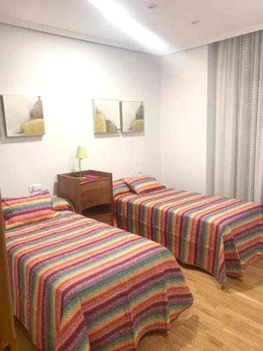 two beds in a hotel room with colorful blankets at 2 bedrooms apartement with city view balcony and wifi at Ciudad Real in Ciudad Real