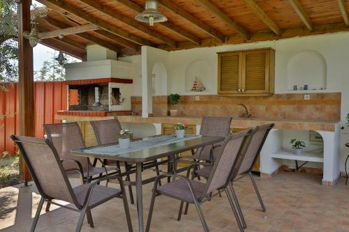 une table et des chaises sur une terrasse avec une cuisine dans l'établissement OlympPlace Olive House-Ground floor, à Leptokaryá