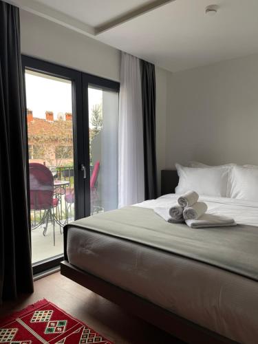 a bedroom with a bed with towels on it and a patio at Etnomania Boutique Hotel in Pristina