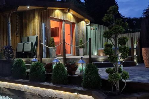 Una casa con un porche con plantas en macetas y luces. en The Wendy house, en Parkend