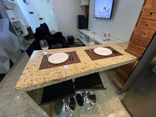 a table with two plates and glasses on it at Apart Hotel Seg Total Lofts Encantadores in Mogi-Guaçu