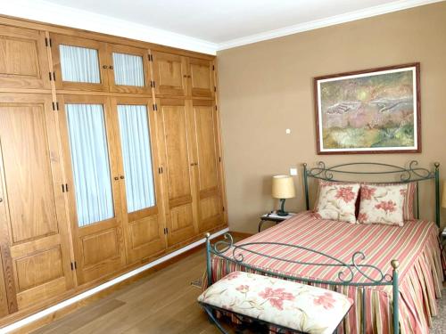 1 dormitorio con 1 cama y armarios de madera en 3 bedrooms villa with shared pool enclosed garden and wifi at Casais de Sao Bras, en Casais de São Brás