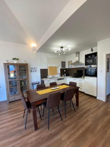 a kitchen and dining room with a wooden table and chairs at Hillside Apartman in Dunaszentmiklós