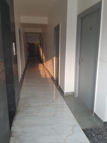 a hallway of a building with white walls and a tile floor at Auro Maison in Puducherry