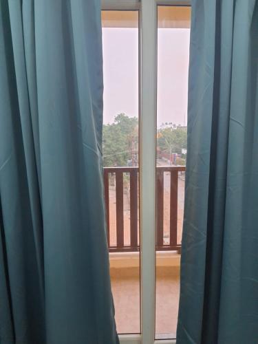 a window with blue curtains looking out at a balcony at Auro Maison in Puducherry