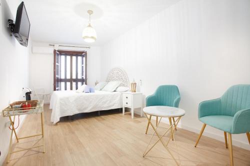 a white bedroom with a bed and two chairs at Altabib Riad in Córdoba